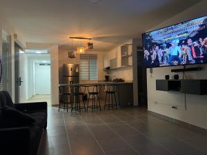 Aqualina Orange Girardot, décimo piso في جيراردو: غرفة معيشة مع مطبخ وتلفزيون على الحائط