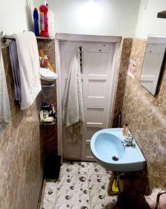 niewielka łazienka z niebieską umywalką i drzwiami w obiekcie Stay near Quest Mall & Don Bosco Park Circus w mieście Kolkata