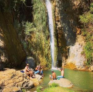 un grupo de personas sentadas en el agua cerca de una cascada en Casa LUNAH Cabalgatas y Meditación, en Valle de Bravo