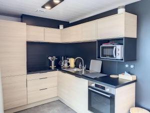 une cuisine avec un évier et un micro-ondes dans l'établissement Chalet à Jullouville - 6 couchages, piscine chauffée, proche plage et commerces - FR-1-361-521, à Jullouville 13 autres photos