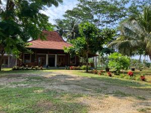 dom z palmą przed nim w obiekcie Puri Sanghyang w mieście Batukaras