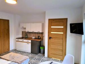 a kitchen with white cabinets and a wooden door at New holiday apartment in Mrze yno in Mrzeżyno
