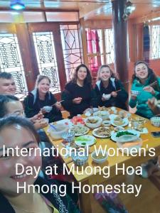 un grupo de mujeres sentadas alrededor de una mesa comiendo comida en Muong Hoa Hmong Homestay, en Sa Pa