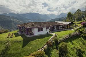 une maison sur un champ verdoyant avec des montagnes en arrière-plan dans l'établissement La Casa en las Nubes, à Salento