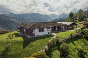 a house on a green field with mountains in the background at La Casa en las Nubes in Salento