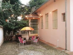 a patio with chairs and an umbrella in front of a house at Casa Patrimônio Histórico - Centro de Uberaba in Uberaba