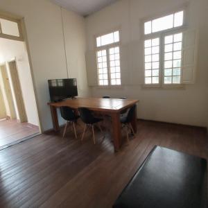 an empty room with a wooden table and two windows at Casa Patrimônio Histórico - Centro de Uberaba in Uberaba