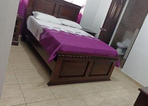 a bed with a purple blanket on top of it at Casa Amplia con Piscina in San Felipe de Puerto Plata