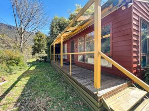 une maison rouge avec un porche en bois avec des fenêtres dans l'établissement Banksia Cottage, à Halls Gap