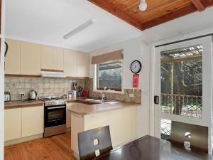une cuisine avec un évier et une horloge murale dans l'établissement Banksia Cottage, à Halls Gap