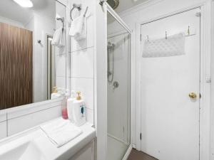 une salle de bain blanche avec lavabo et douche dans l'établissement Banksia Cottage, à Halls Gap 4 autres photos