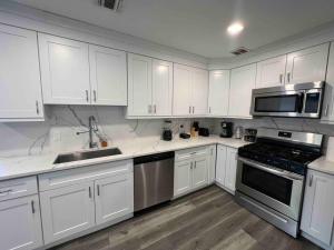 una cocina con armarios blancos y electrodomésticos de acero inoxidable en The Classy Suite - 2BR with Free Parking, en Paterson
