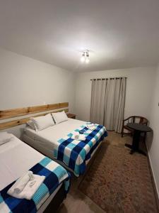 1 dormitorio con 2 camas, mesa y silla en Villa Rural, en Campos do Jordão