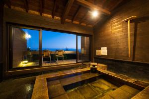 a bath tub in a room with a large window at Spagreenness in Kokonoe