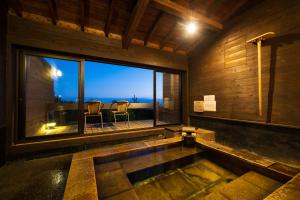 a bath tub in a room with a large window at Spagreenness in Kokonoe