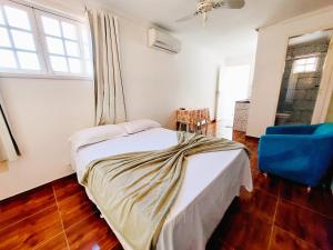 - une chambre avec un lit et une chaise bleue dans l'établissement Suítes do Marcelo 301, à Cabo Frio