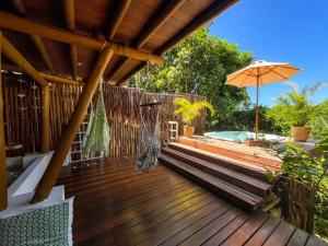 una terraza de madera con hamaca y sombrilla en Locanda Ariramba, en Santa Cruz Cabrália