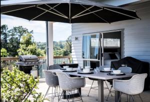 a table with chairs and an umbrella on a patio at Tauranga Luxury Getaway in Tauranga
