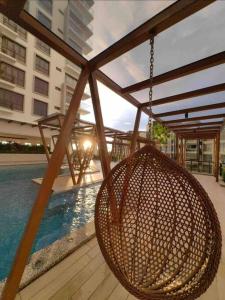 a rattan basket hanging from a patio with a pool at K Avenue Cozy Family Suites 4-6 pax 亚庇国际机场5分钟 in Donggongon