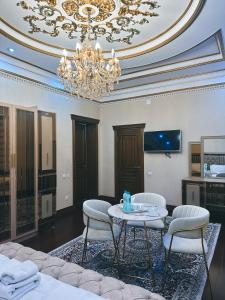 uma sala de estar com um lustre e uma mesa e cadeiras em CITY GARDEN HOTEL em Dushanbe