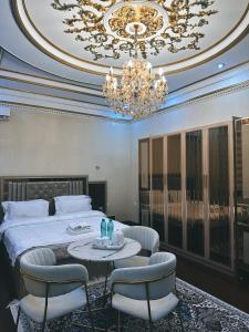 a bedroom with a bed and chairs and a chandelier at CITY GARDEN HOTEL in Dushanbe