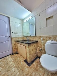 a bathroom with a toilet and a sink and a mirror at Park Breeze Penthouse in Bangalore