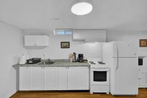 a kitchen with white cabinets and a white refrigerator at Cozy Lower Level 2BR Apartment in Barrie