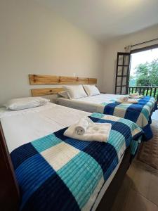 three beds in a room with towels on them at Villa Rural in Campos do Jordão