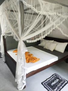 um quarto com uma cama de dossel com cortinas brancas em AURORA Midigama em Ahangama