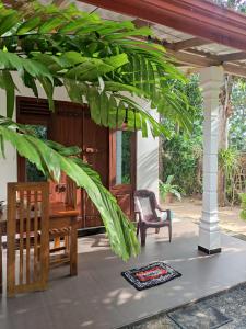 eine Veranda mit einer Bank, einem Tisch und einem Stuhl in der Unterkunft AURORA Midigama in Ahangama