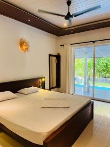 a bedroom with a large bed and a large window at SuSha Happy Three Villa in Hikkaduwa