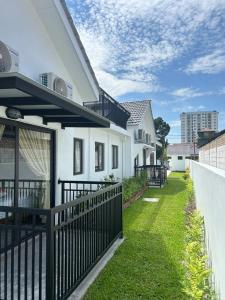 a white house with a black fence and grass at The Farmhouse in Ipoh