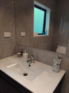 uma casa de banho com um lavatório branco e um espelho. em HomeStay! Close to Airport, bus & Train station em Auckland