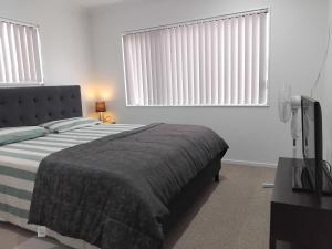 um quarto com uma cama e duas janelas com persianas em HomeStay! Close to Airport, bus & Train station em Auckland