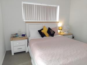 um quarto com uma cama branca e almofadas amarelas em HomeStay! Close to Airport, bus & Train station em Auckland