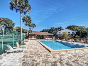 a swimming pool with chairs and a palm tree at Amelia Island Paradise Rental! in Fernandina Beach