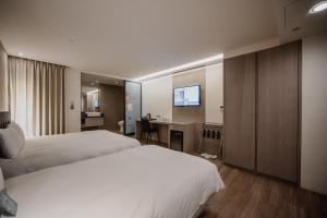 Habitación de hotel con 2 camas y escritorio en Hub Hotel Kaohsiung Yawan Branch, en Kaohsiung