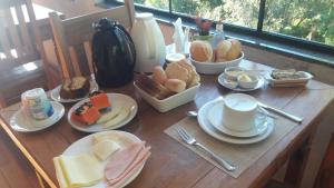 ein Holztisch mit Tellern voller Essen darauf in der Unterkunft Villa Rural in Campos do Jordão