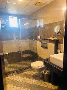 y baño con ducha, aseo y lavamanos. en Hotel Excalibur, en Kottayam