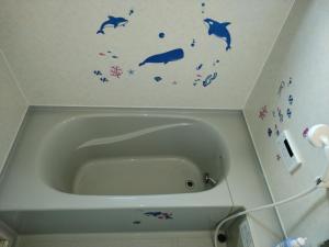 La salle de bains est pourvue d'une baignoire avec des peintures murales de poisson. dans l'établissement シーカレント　ゆな　CHIKURA, à Chikura