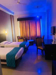 Habitación de hotel con 2 camas, mesa y sillas en Hotel Excalibur en Kottayam