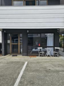 a building with two chairs and a table in the window at Catlins area accommodation in Owaka