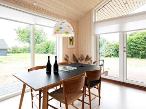 a dining room with a table and chairs and windows at 5 person holiday home in Haarby in Brunshuse