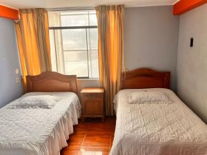 twee bedden in een kamer met een raam bij Hostal El Rancho in Huancayo