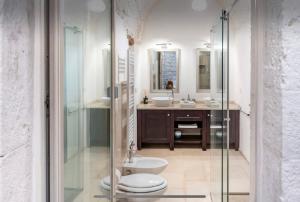 La salle de bains est pourvue de toilettes et d'une douche en verre. dans l'établissement Suite centro storico, à Locorotondo