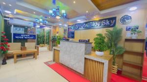 ダッカにあるHotel Blue Sky Mirpurの青い空の看板と植物が飾られたホテルロビー