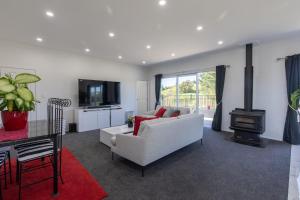 a living room with a white couch and a fireplace at Oasis Rural Retreat in Norsewood