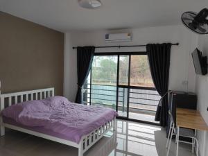 a bedroom with a bed and a large window at Flourish Homes ฟลอริชโฮมส์ ห้องพัก มอเกษตร สกลนคร in Ban Na Oi