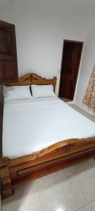 a bedroom with a wooden bed with white sheets at Los Pinos in Jardin