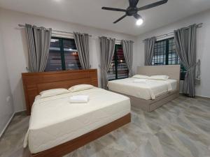 een slaapkamer met 2 bedden en een plafondventilator bij Lubuk Private Villa Langkawi with Jacuzzi Pool in Kuah